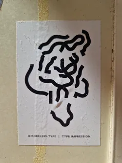 A white sticker with black abstract typographic design. The text at the bottom reads '@MORELESS.TYPE | TYPE IMPRESSION'