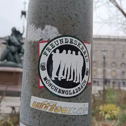 Sticker featuring a group of friends with beer mugs. The text on the sticker says "Freundeskreis Mönchengladbach". There is also a smaller sticker underneath with the website ufftour.de