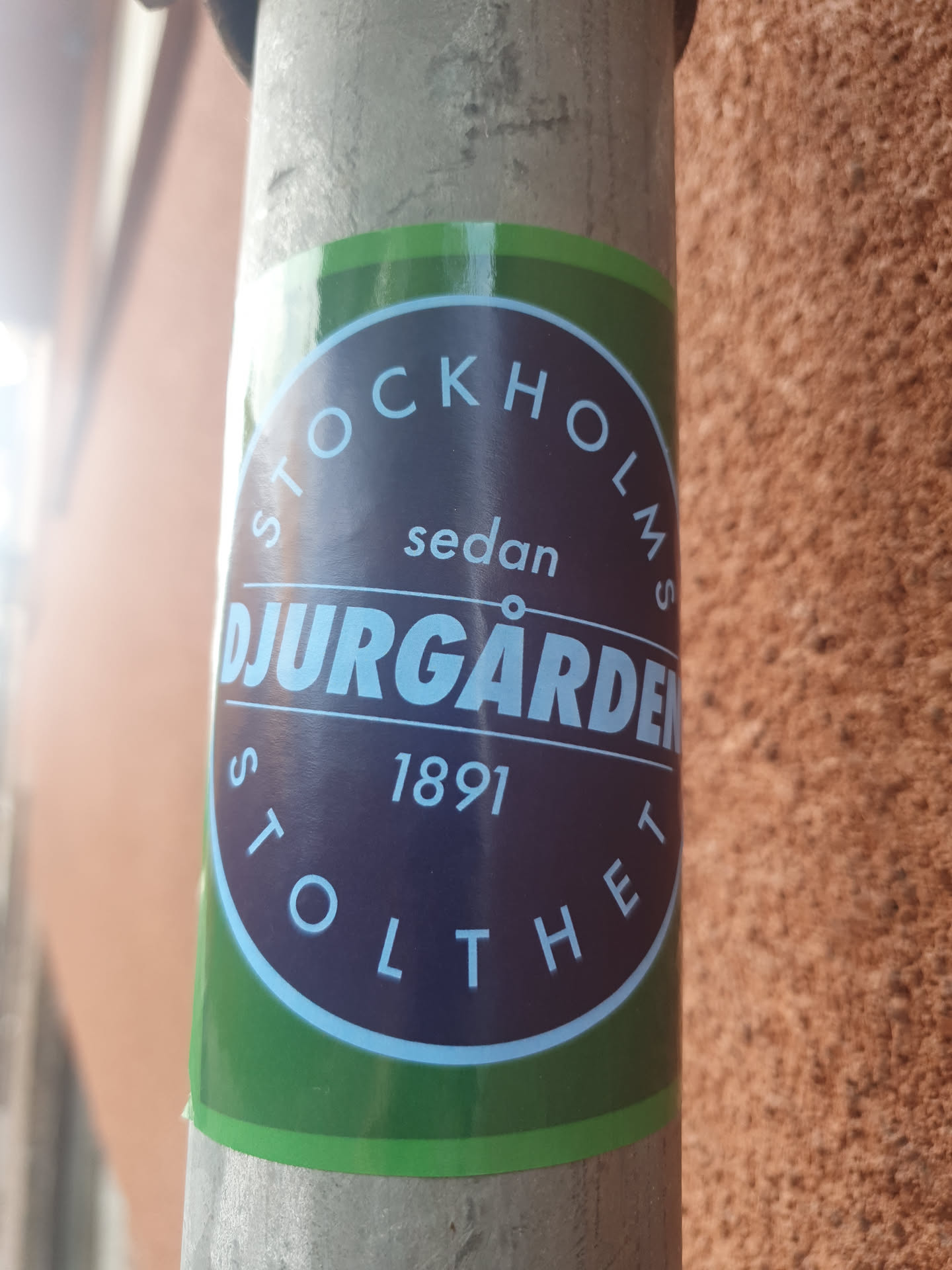 A round sticker with green and purple colors. It says 'Stockholms sedan Djurgården 1891 Stolthet' which translates to 'Stockholm since Djurgården 1891 Pride'