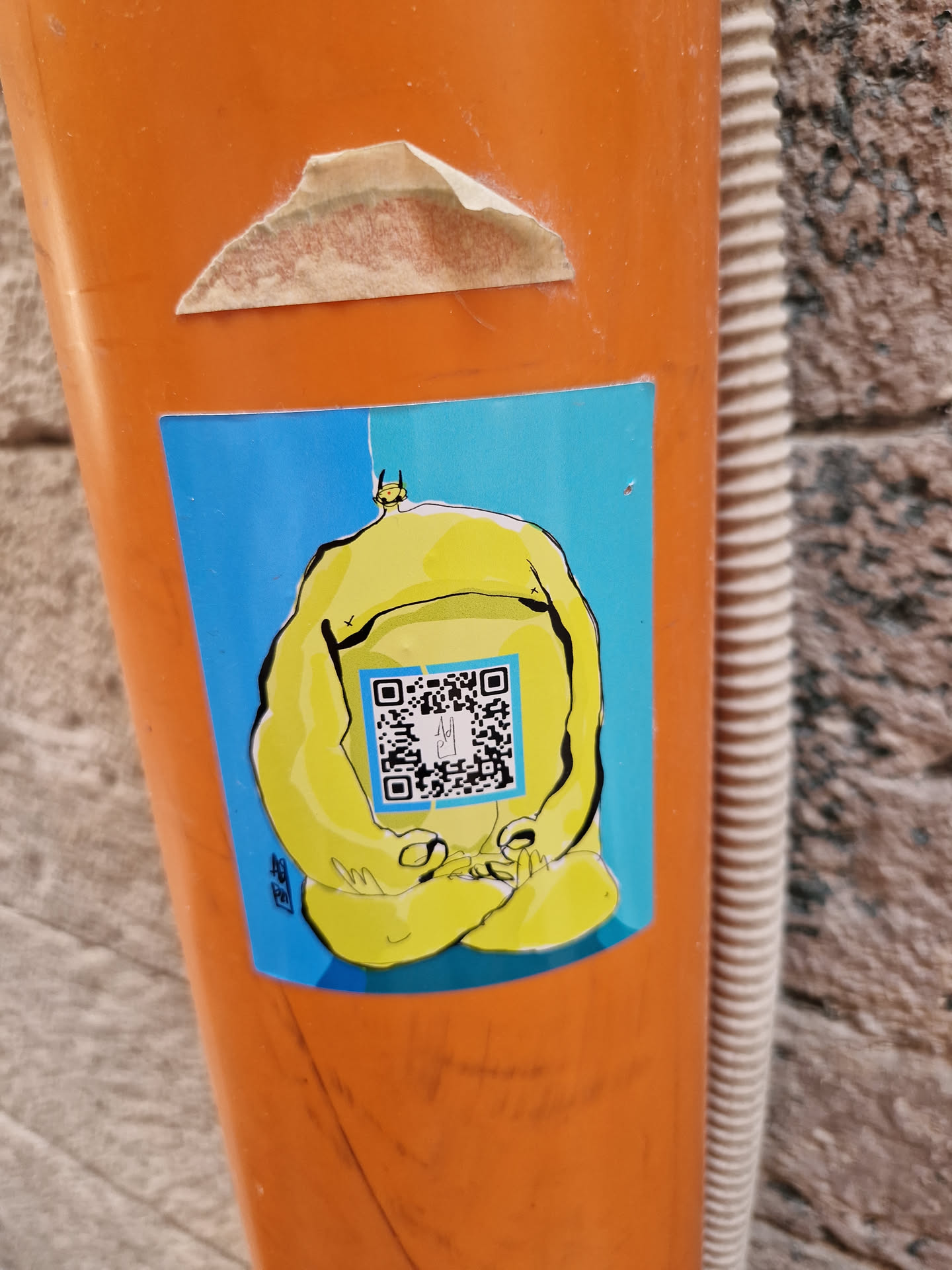A yellow cartoon character in a zen pose is featured on this sticker.  The character has a simplistic design and is sitting peacefully. A QR code is prominently displayed on the character's stomach. The sticker has a bright blue background.