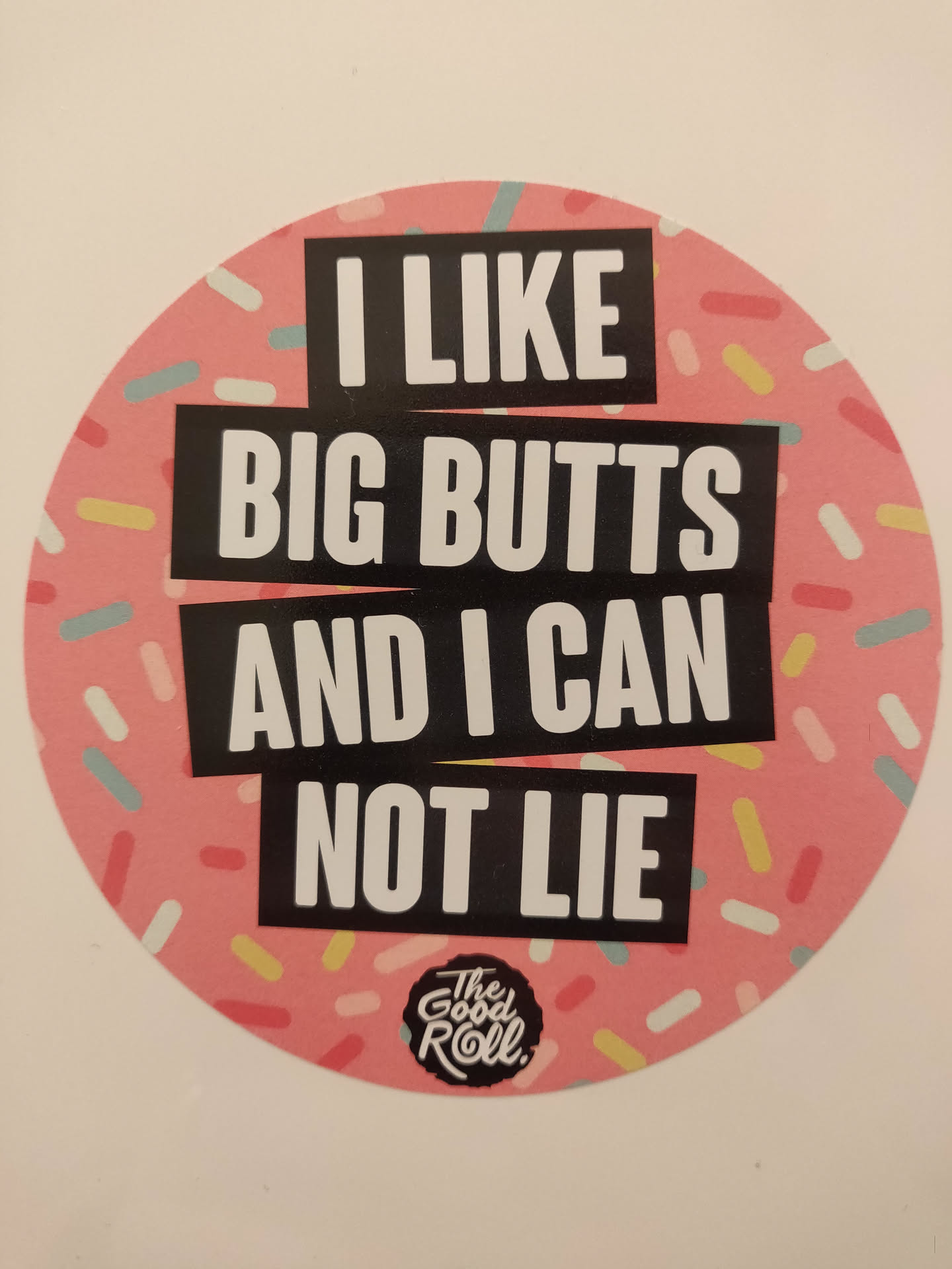 Round sticker with a pink background and colorful sprinkles.  The text 'I LIKE BIG BUTTS AND I CAN NOT LIE' is written in black bold letters on the sticker. The logo 'The Good Roll' is also visible at the bottom.