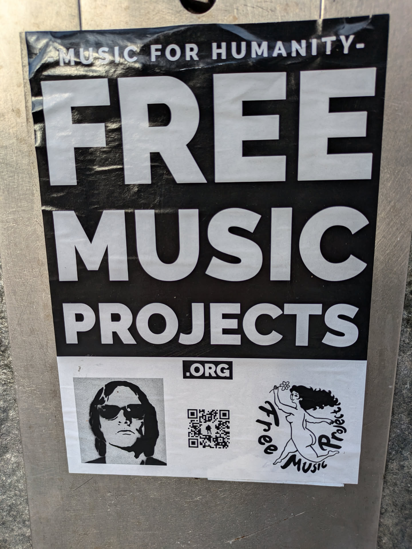 A sticker promoting Free Music Projects, an organization dedicated to providing free music. The sticker features a QR code, a logo with a woman dancing, and a portrait of a person wearing sunglasses.