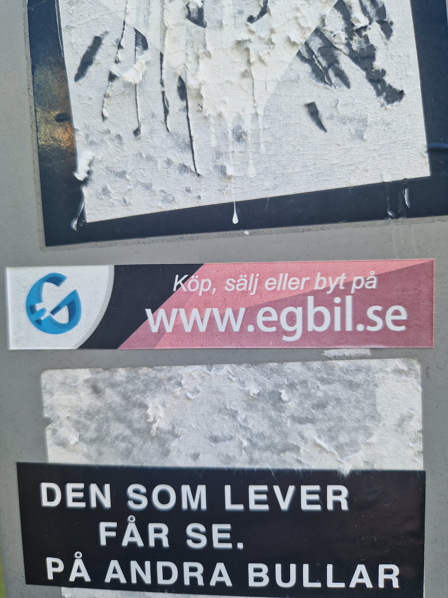 A sticker with a quote in Swedish. It says: "He who lives will see. On other buns." It's placed on top of another sticker which advertises a website.