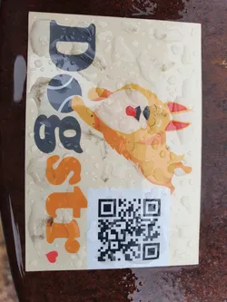 A wet dog sticker with a QR code. The sticker features an illustration of a happy dog carrying a ball. The text on the sticker says "Doggo's Best Friend".