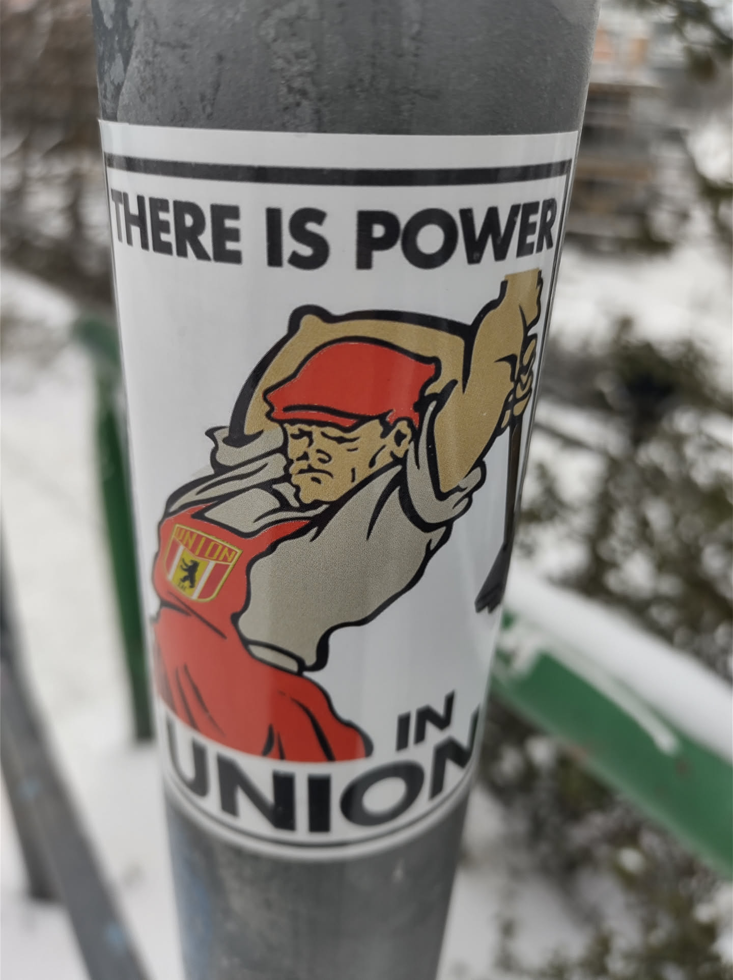A sticker featuring a cartoon illustration of a person with a red hat and apron wielding a large hammer. The text on the sticker reads "There is power in union".  There is a small emblem on the apron.