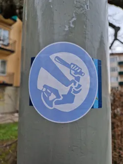 A sticker on a pole depicting a hand holding a baton being stopped by another hand.  It's a symbol of protest against police violence.