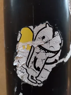 A worn sticker featuring a cartoon creature with a yellow object on its back. The style is simple and slightly distressed, giving it a vintage feel.  The text 'ST MOR' is partially visible on the sticker.