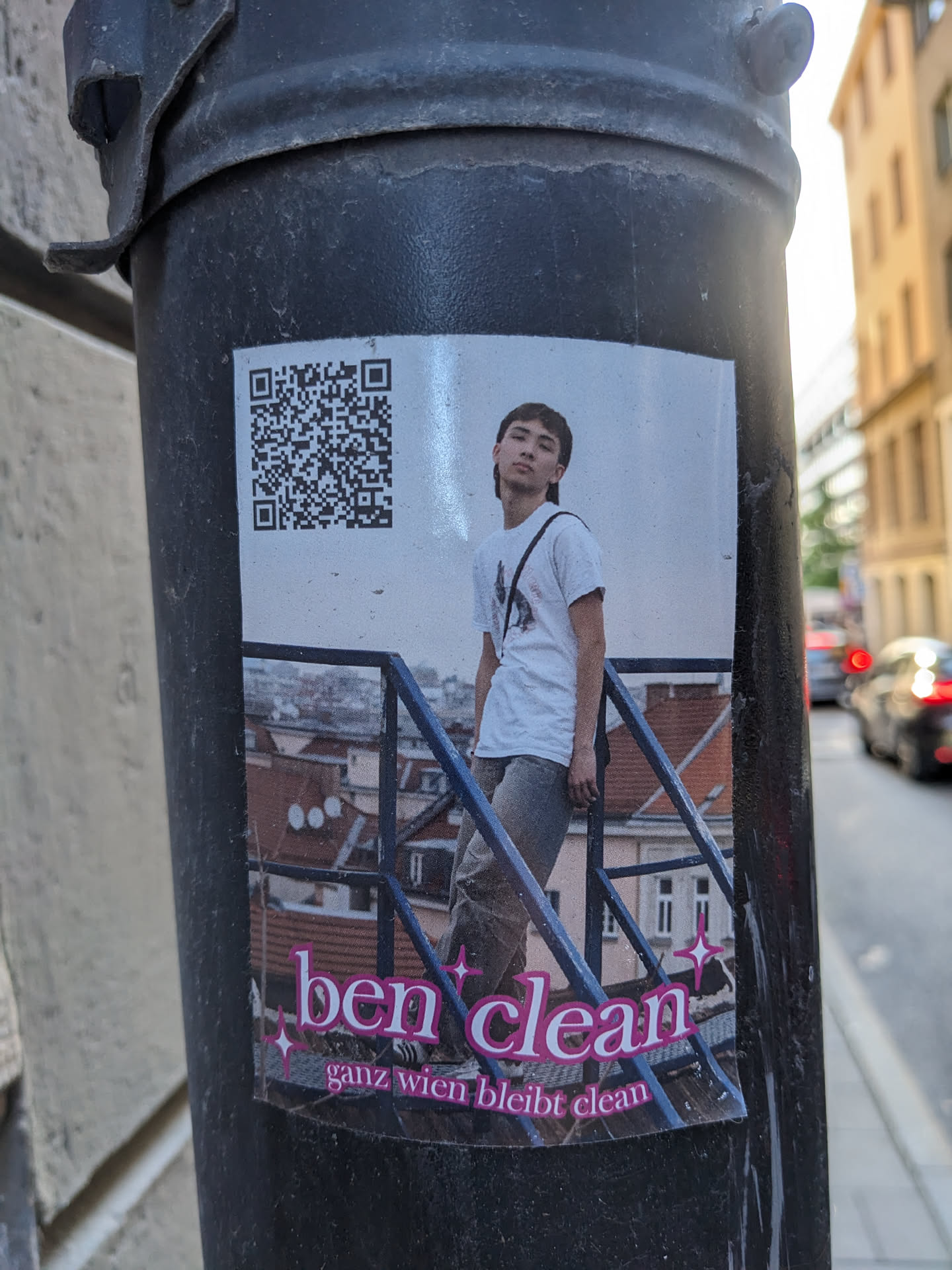 A sticker featuring a photo of a young man standing on a railing, with a QR code and the text "ben clean" and "ganz wien bleibt clean".