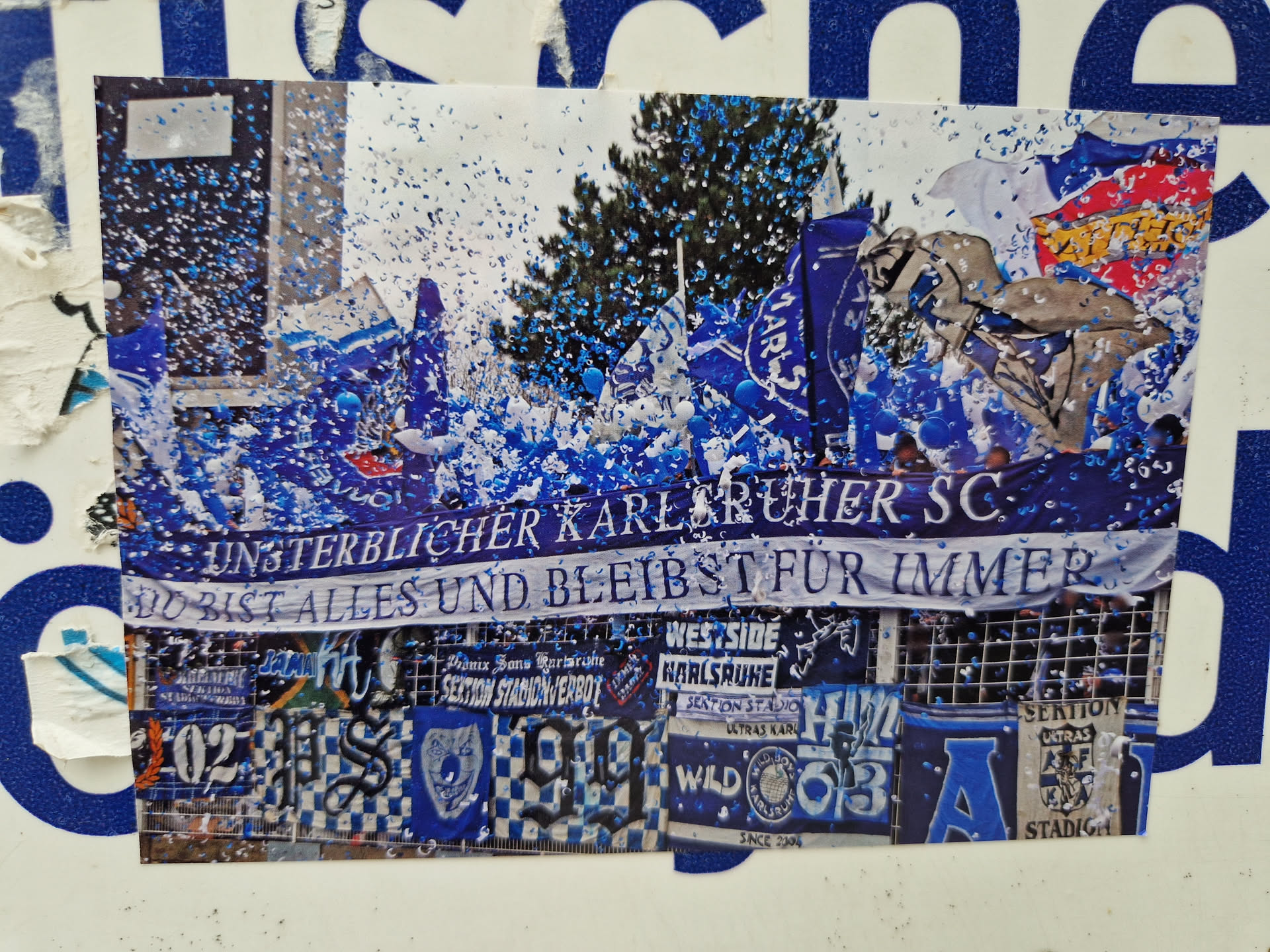 A sticker depicting a celebratory scene of Karlsruher SC fans amidst blue confetti.  The main banner reads "Unsterblicher Karlsruher SC: Du bist alles und bleibst für immer" (Immortal Karlsruher SC: You are everything and remain forever).  The sticker also features various other fan club banners and designs.