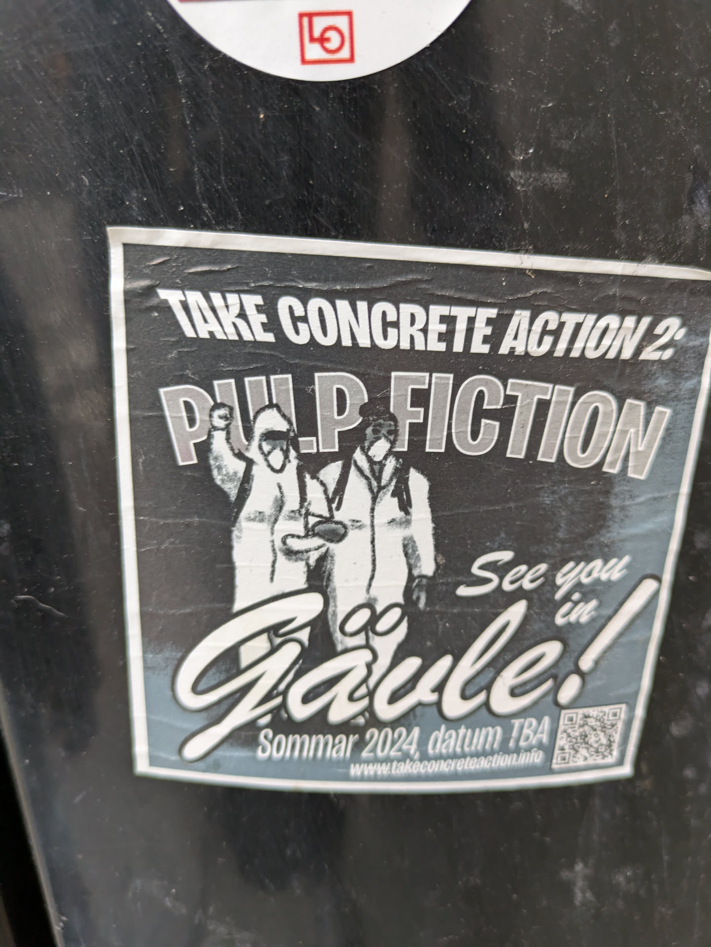 A black and white sticker advertising an event called "Take Concrete Action 2: Pulp Fiction" in Gävle, Sweden during Summer 2024.  The sticker features an illustration of two figures in hazmat suits. A QR code is included.
