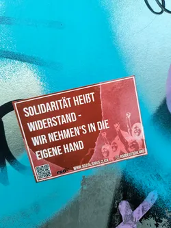 A sticker promoting socialist ideals and direct action.  It features a graphic of raised fists and text in German. A QR code links to www.sozialismus.click. The RSODEutschland logo is visible in the bottom right corner.
