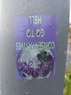 A sticker featuring a full moon and the text "Go to hell Conservatives". The sticker is predominantly purple with green text and has an artist signature on the bottom right corner.