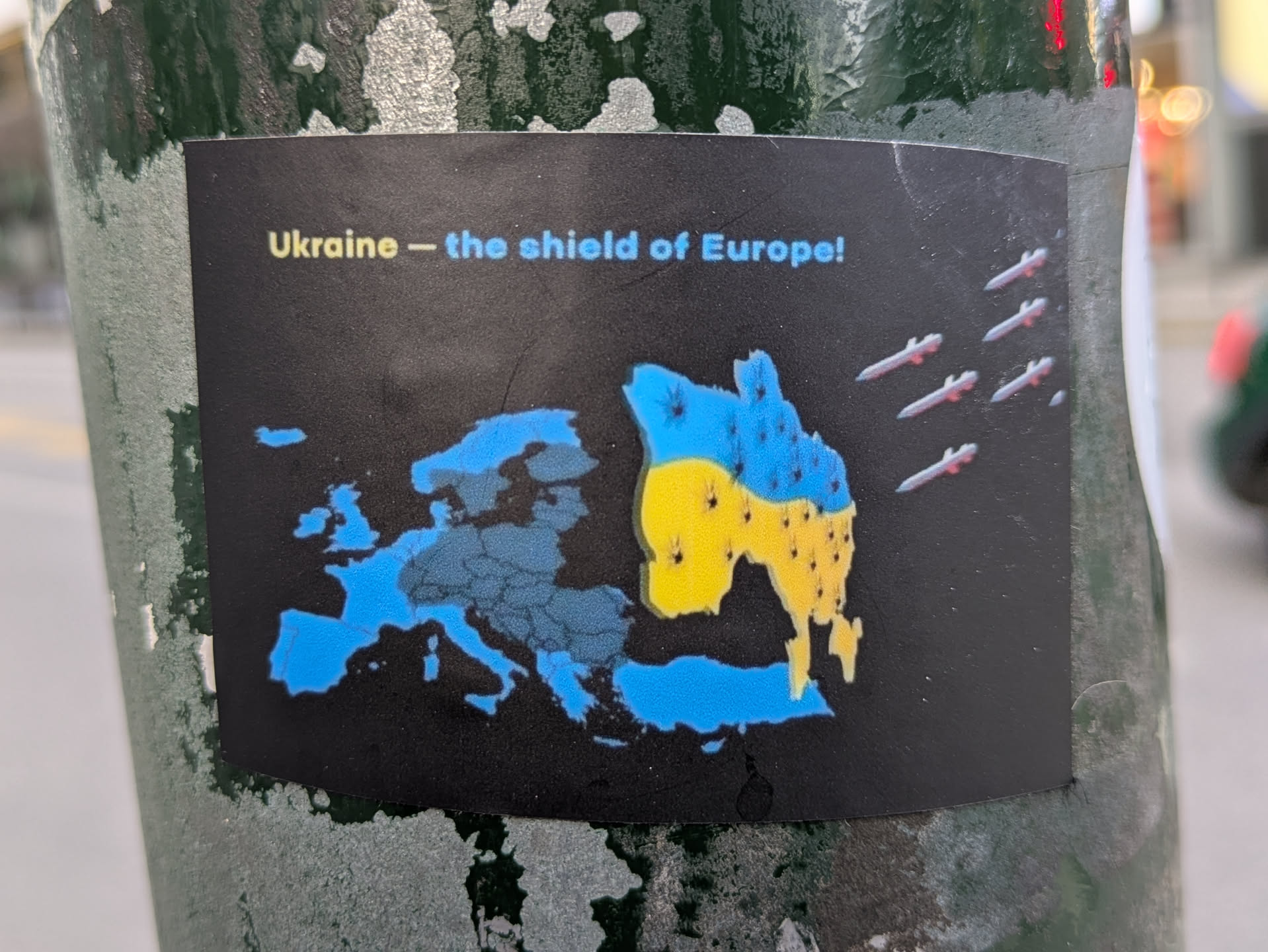 A sticker depicting a map of Europe with Ukraine highlighted in the colors of the Ukrainian flag. Missiles are shown flying towards Ukraine. The text on the sticker reads "Ukraine - the shield of Europe!"