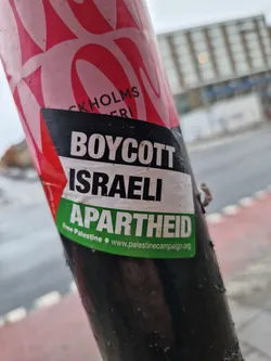 A sticker expressing opposition to Israeli policies. It features the text "Boycott Israeli Apartheid" and a website address.