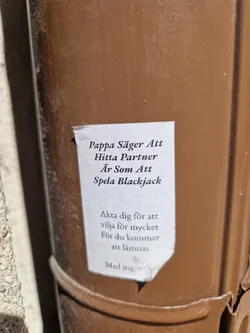 A sticker on a brown pipe with a quote about finding a partner, comparing it to playing blackjack and warning against wanting too much.
