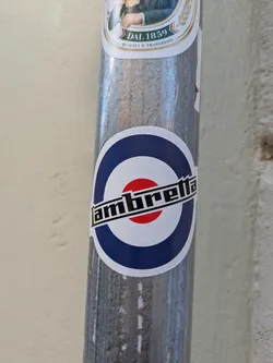 A Lambretta sticker featuring the brand logo with the iconic mod target, affixed to a pole.