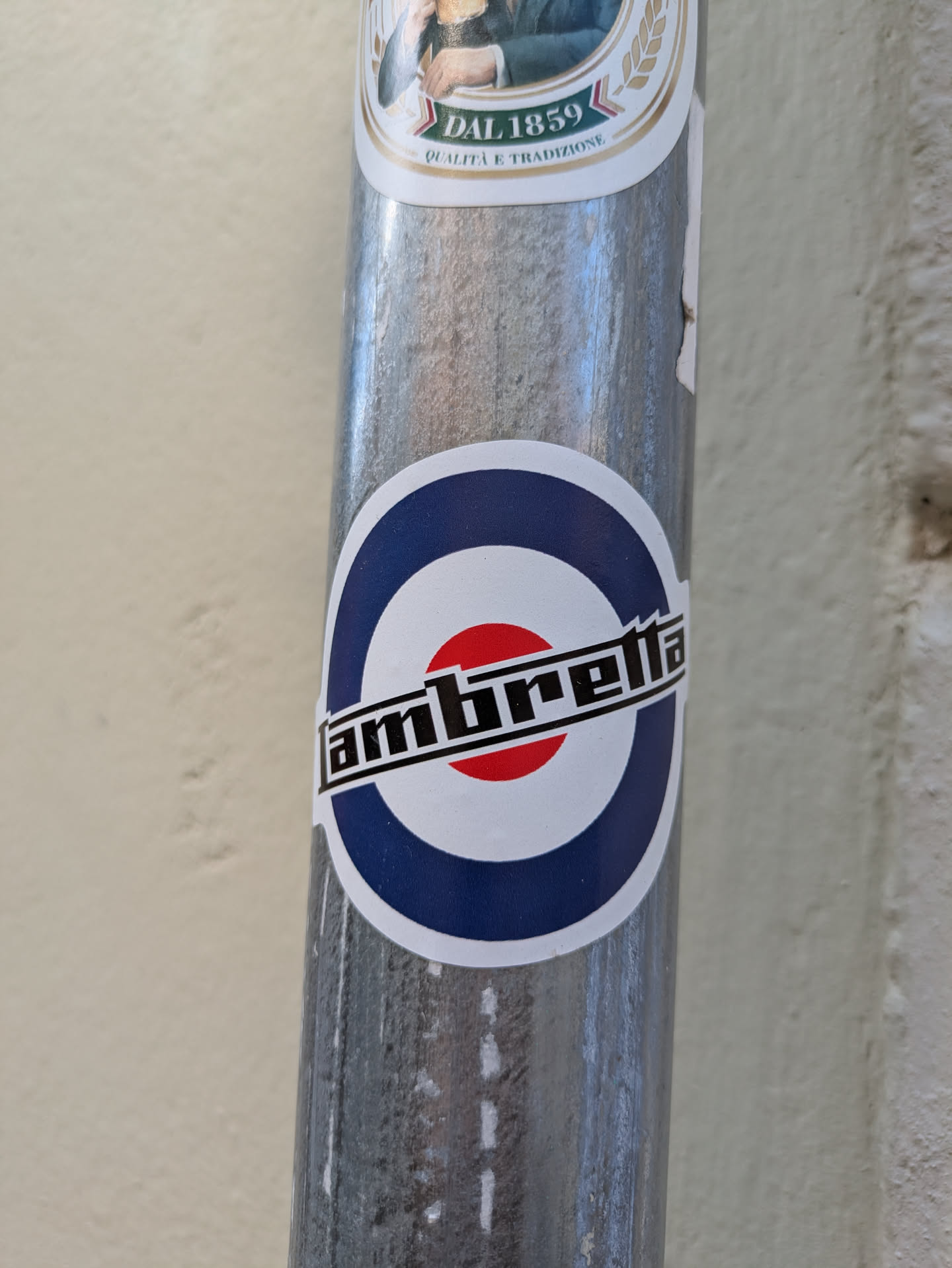 A Lambretta sticker featuring the brand logo with the iconic mod target, affixed to a pole.