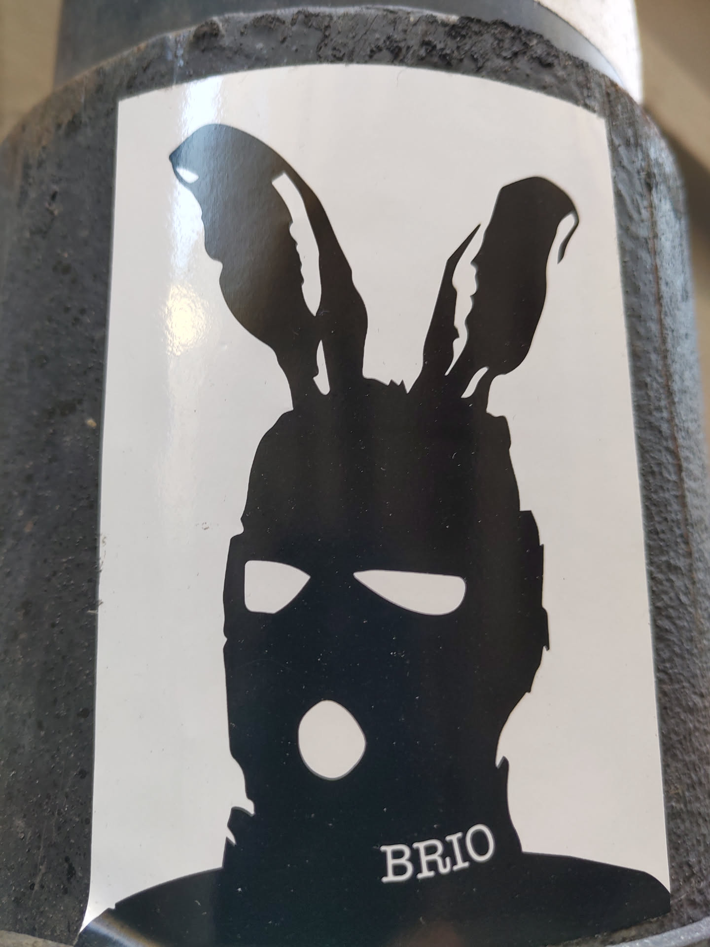 The sticker features a minimalist design of a person wearing a balaclava and bunny ears, creating a stark contrast between the anonymous mask and the playful ears. The artist's signature or brand name is "BRIO", subtly placed at the bottom.
