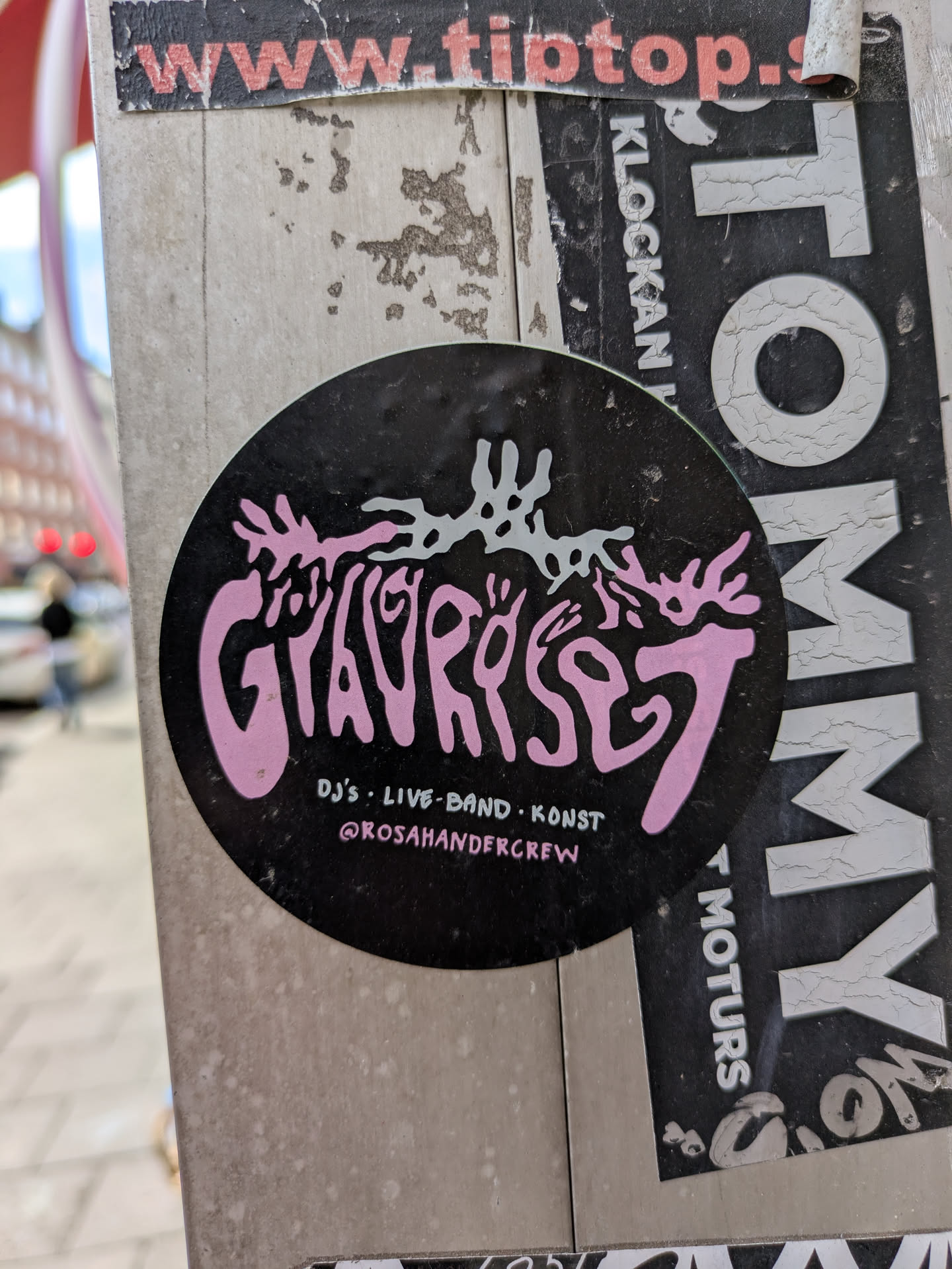 This is a round sticker with a black background. The main text 'GYAVRYSET' is prominently displayed in a decorative, stylized font in pink. Above the text, there's a white abstract graphic. Below the main text, it says 'DJ'S . LIVE-BAND . KONS' and the Instagram handle '@ROSAHANDERCREW'.