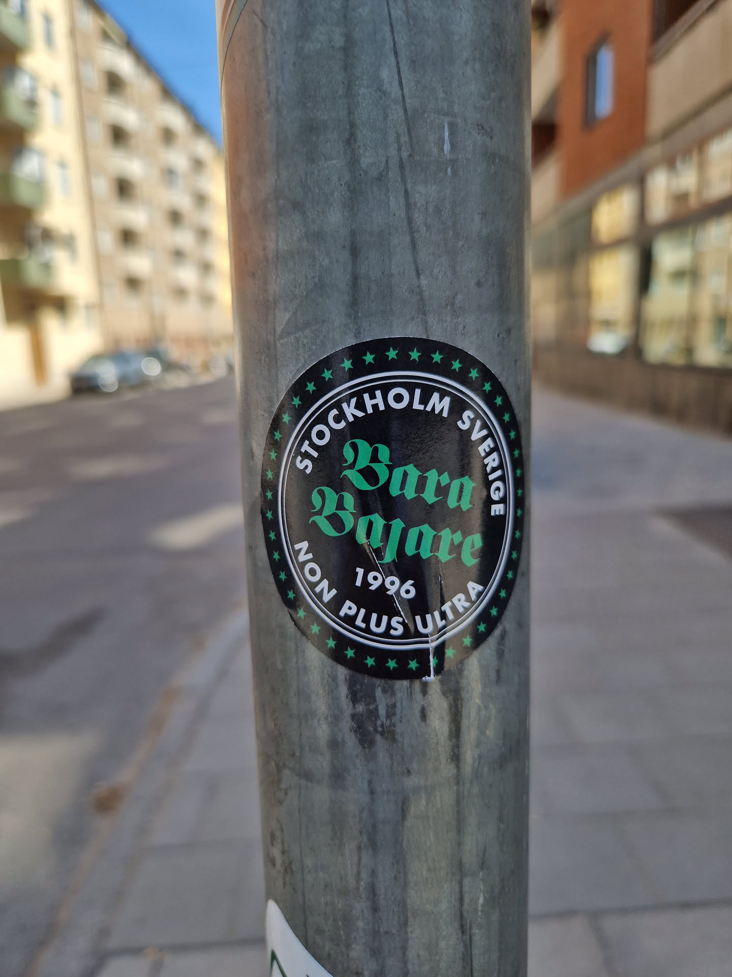 A round sticker with the text "STOCKHOLM SVERIGE" at the top and "Bara Bajare" in a stylized font in the center.  The year 1996 and "NON PLUS ULTRA" are written below.  The sticker has a dark background with green text and white stars.