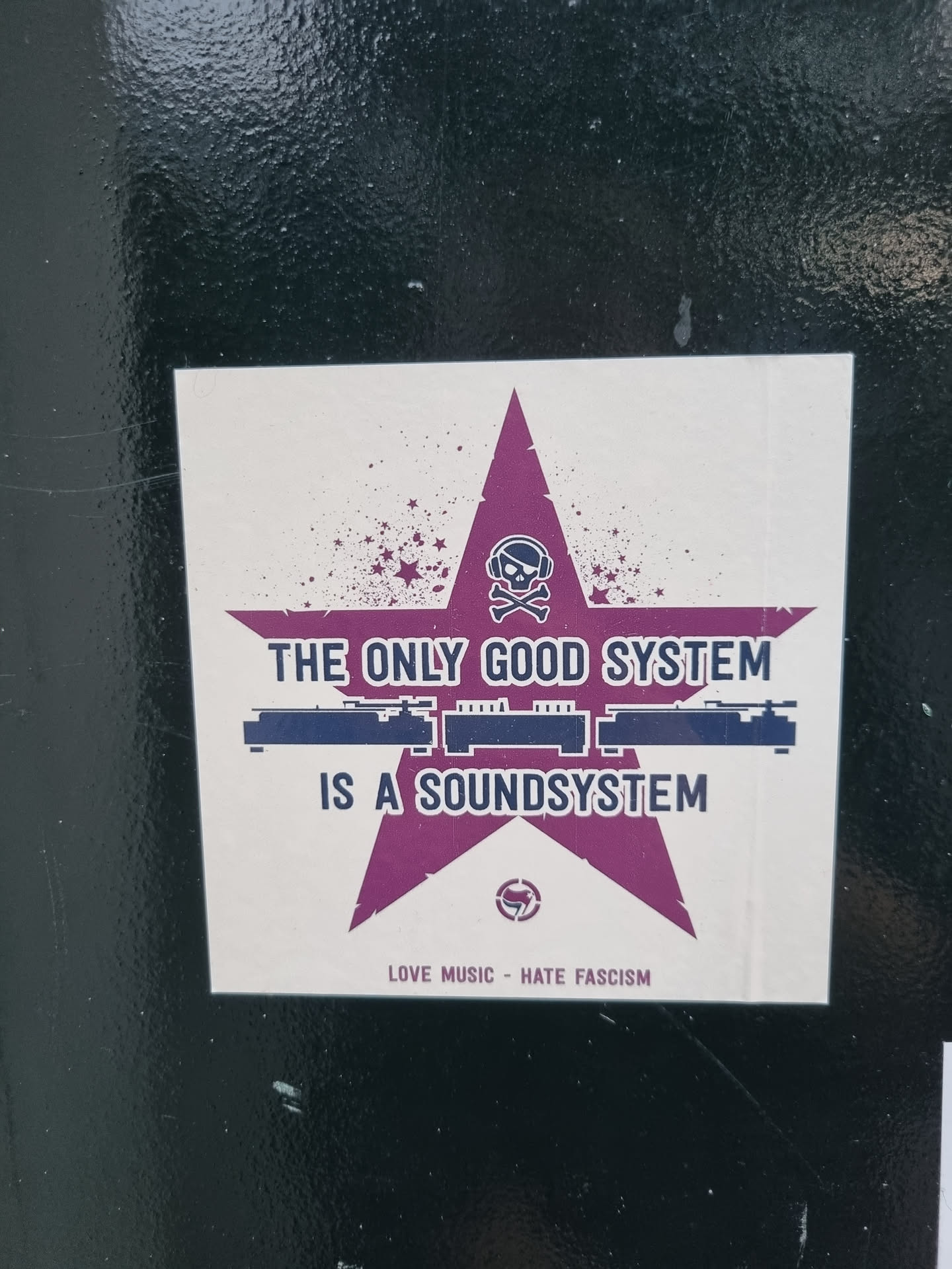 A sticker featuring a purple star with a skull and crossbones, sound system graphic, and the text "The only good system is a soundsystem."  Below is the text: "Love Music - Hate Fascism"