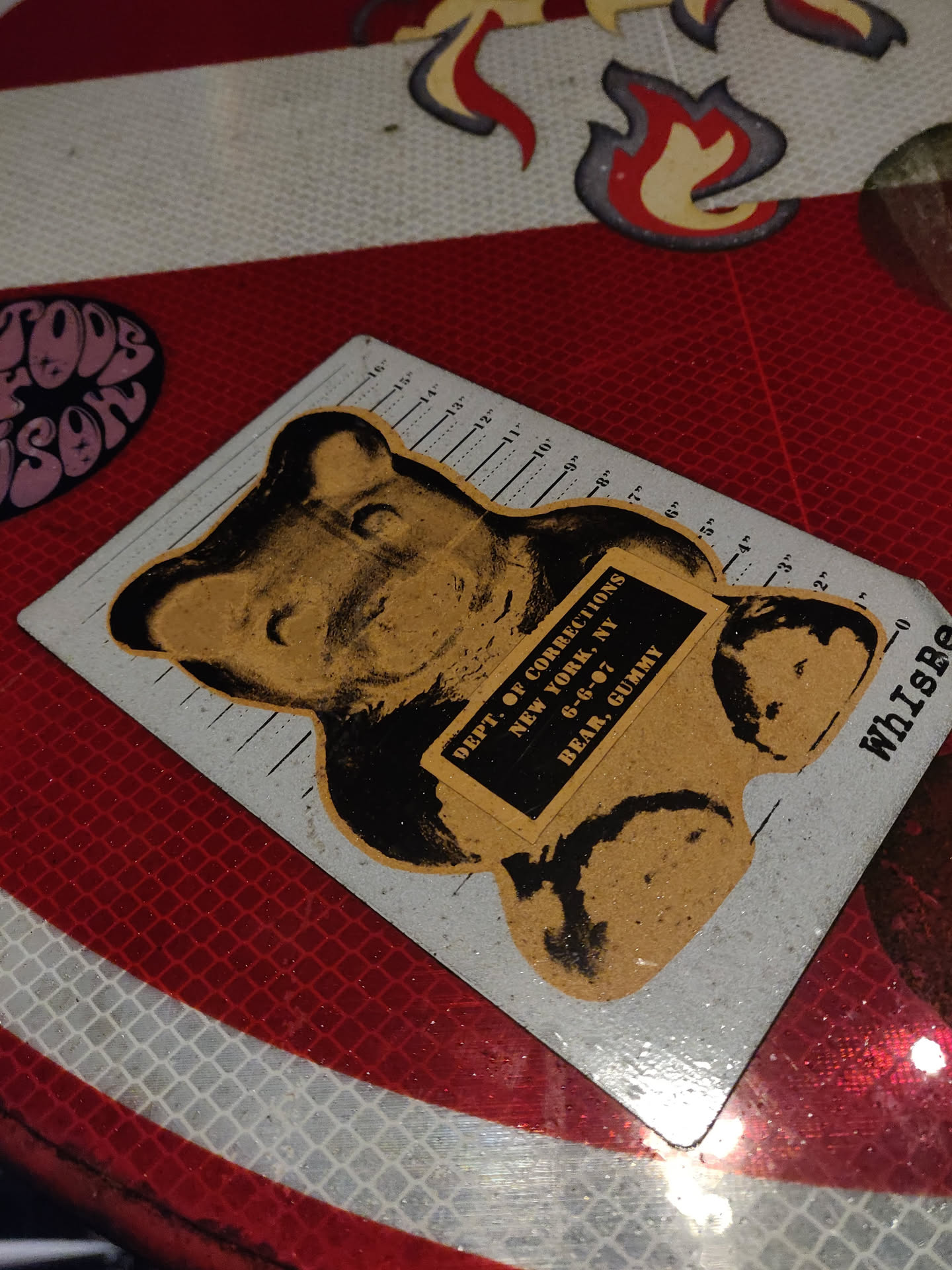 A sticker featuring a gummy bear with a mugshot-style design. The text on the sticker reads "DEPT. OF CORRECTIONS NEW YORK, NY 6-6-07 BEAR, GUMMY".