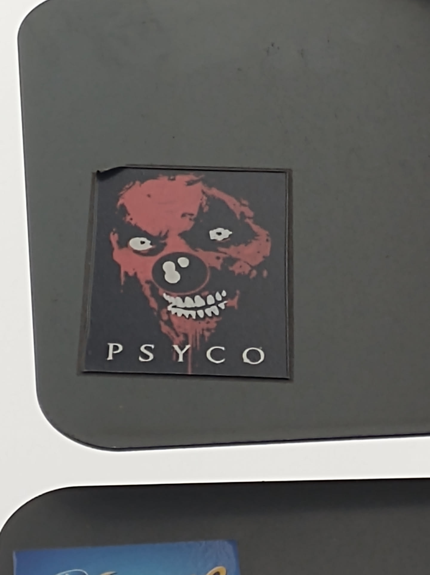 A sticker featuring a scary clown face with the word "PSYCO" written underneath. The clown is depicted in red and black, with a bloody grin and large, white eyes.