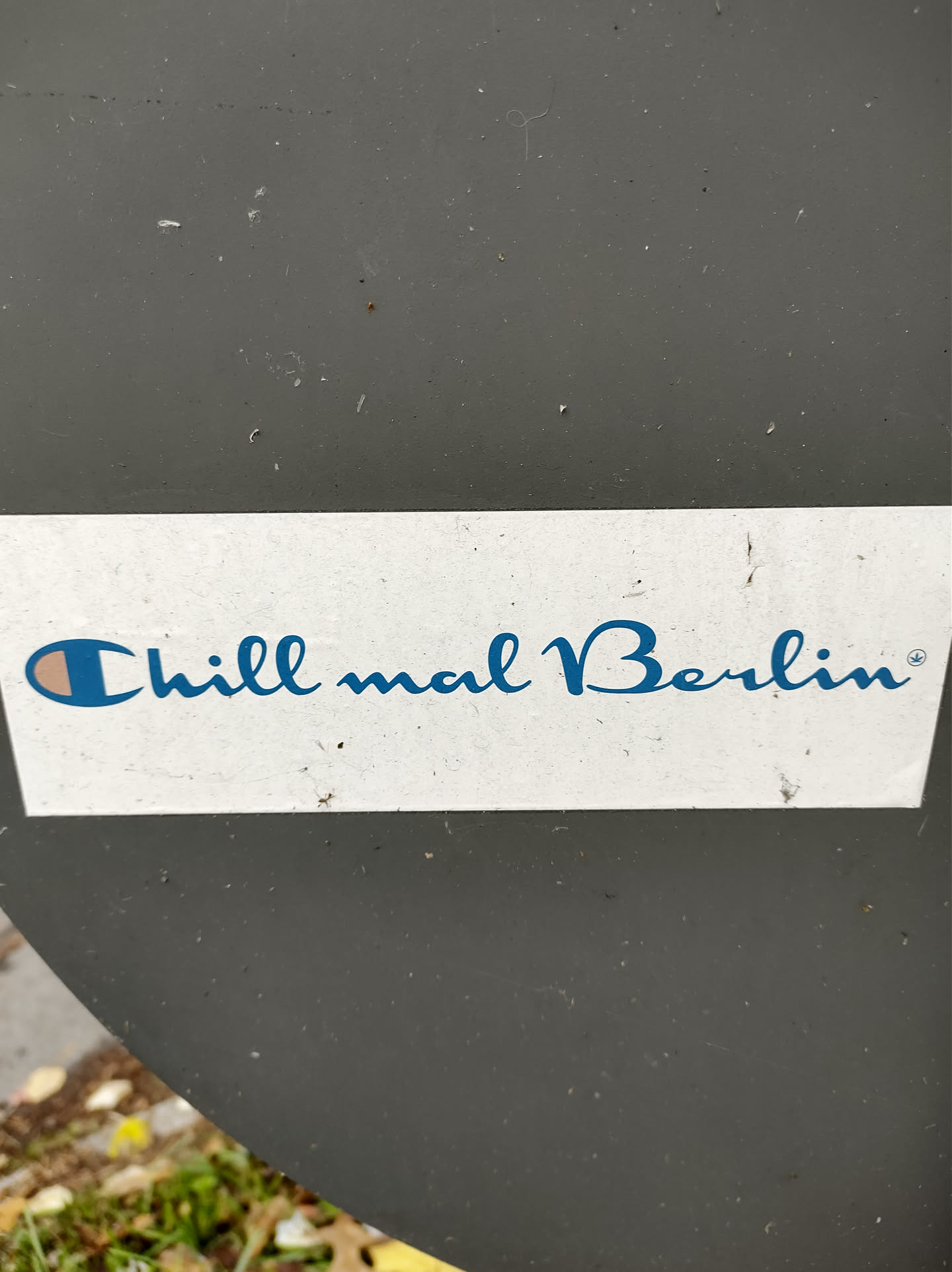 A sticker with the text "Chill mail Berlin" in a blue cursive font.  The left side of the text features a small Champion logo.