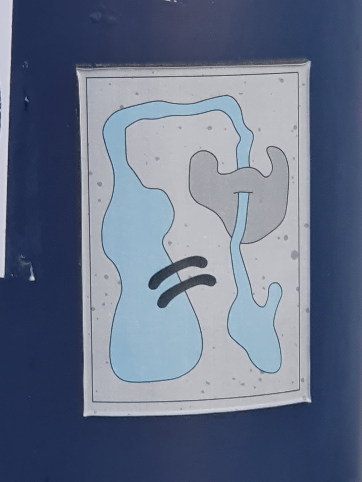 A sticker with an abstract design featuring blue and grey shapes on a light grey background. The shapes appear organic and fluid, resembling a minimalist landscape or map.  The sticker has a slightly worn or speckled appearance.