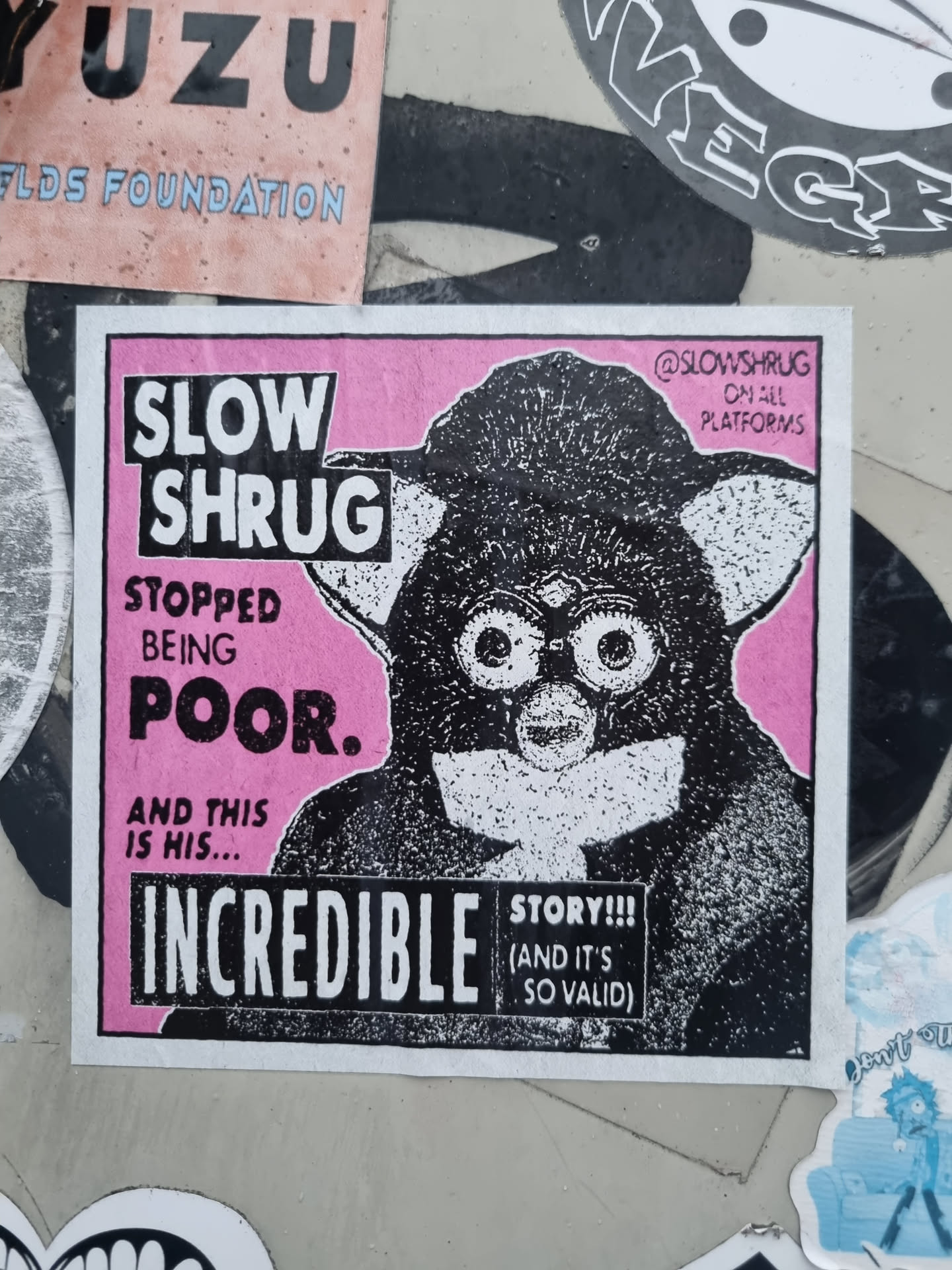 Pink and black sticker featuring an illustration of a Furby-like creature with the text "Slow Shrug", "Stopped being poor." and "Incredible."  The sticker also includes the text "Story!!! (and it's so valid)" and the social media handle @slowshrug.