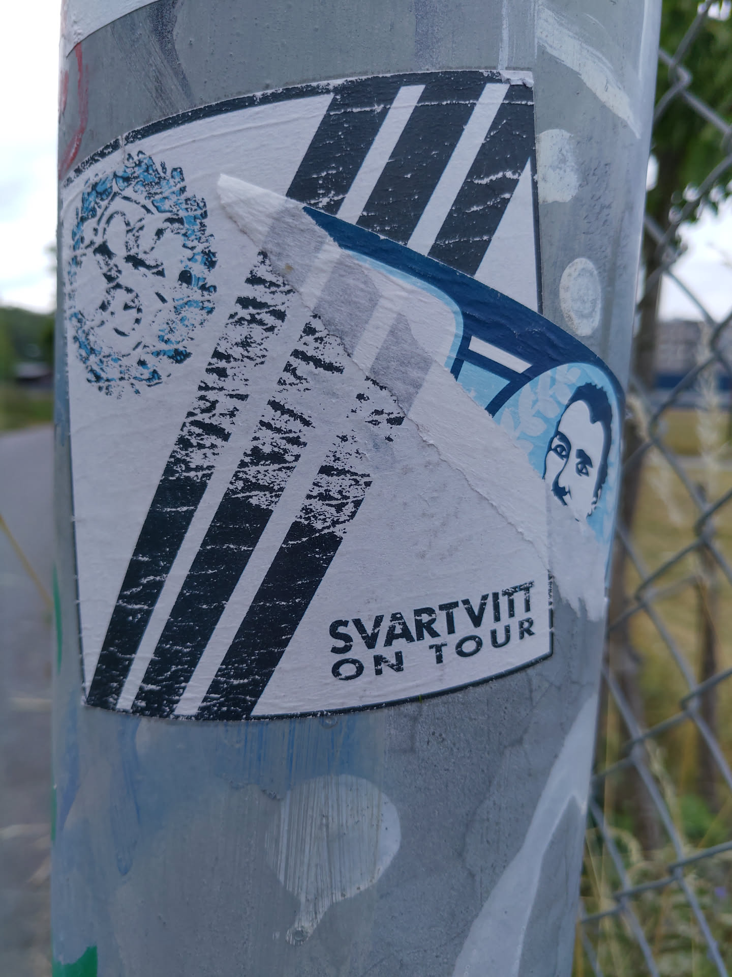 A worn sticker featuring diagonal stripes, a portrait, and the text "SVARTVITT ON TOUR".