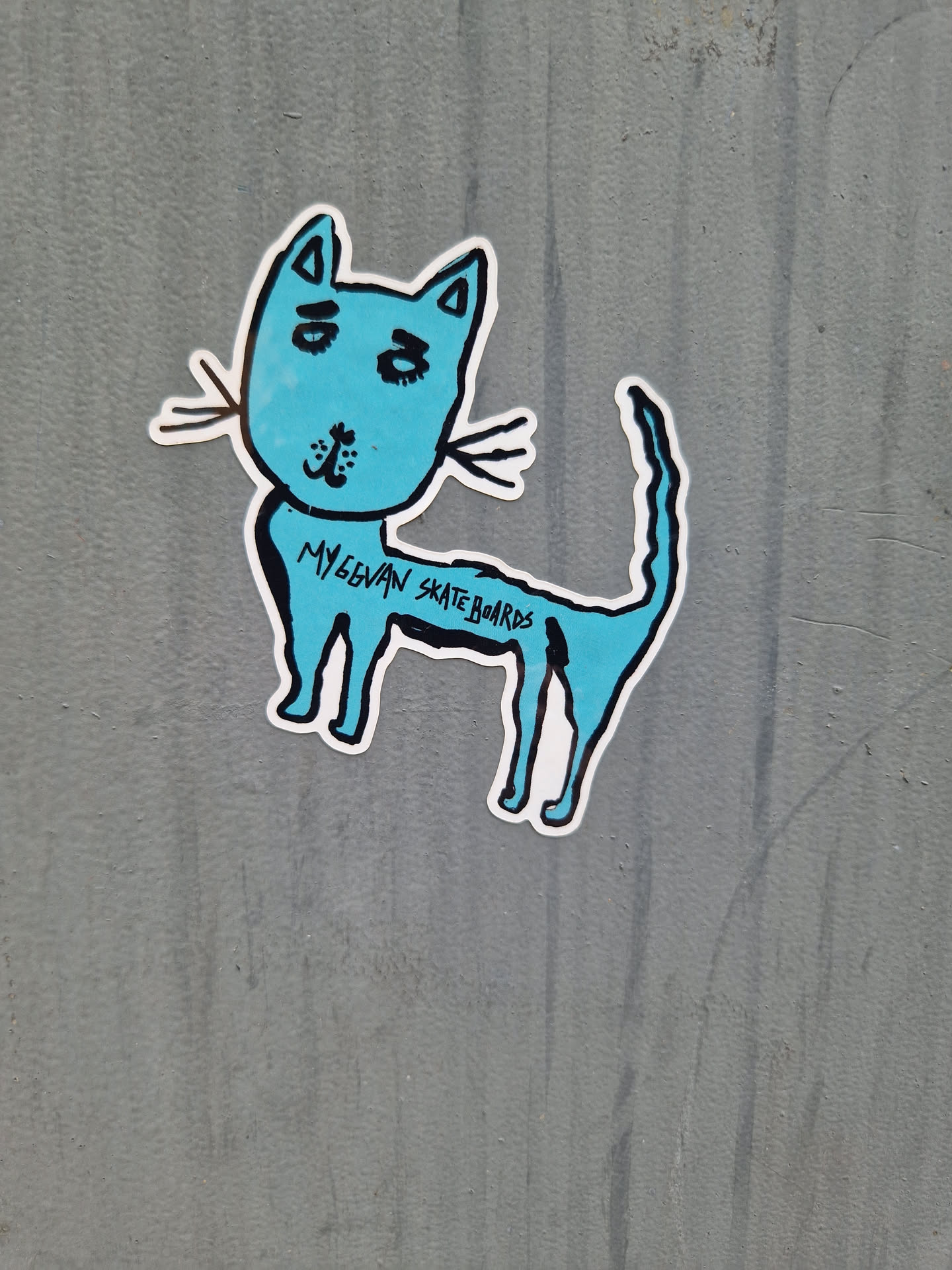 A light blue sticker of a simple cartoon cat. The text 'MyGowan Skateboards' is written on the cat's body. 