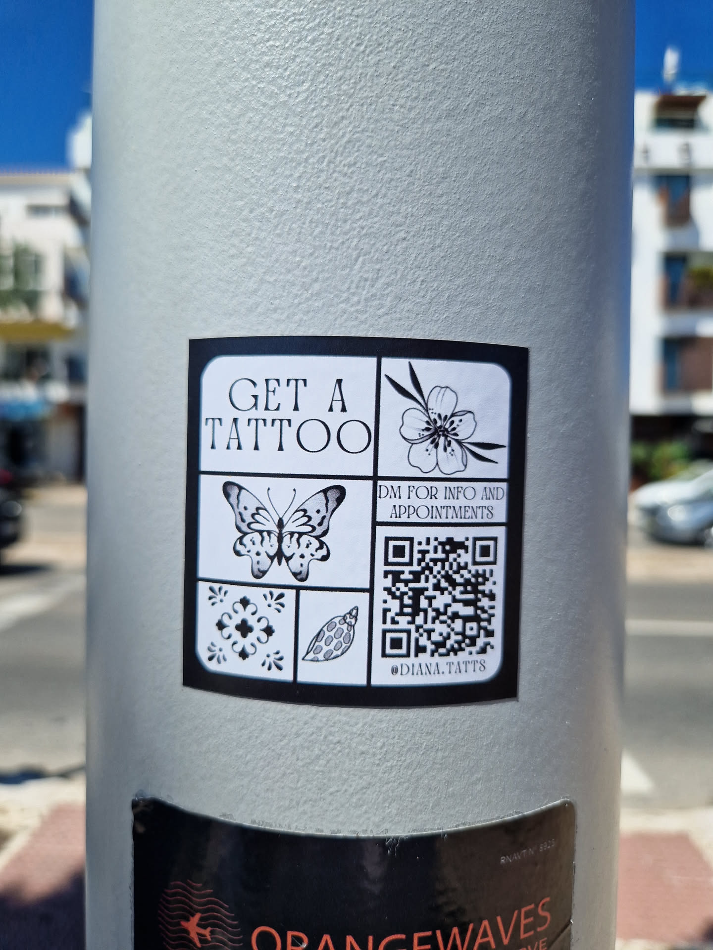 A sticker with a QR code and the text "GET A TATTOO" and "DM FOR INFO AND APPOINTMENTS". It also contains images of a butterfly, flower, and other small design elements. The Instagram handle @DHMA.TATT8 is also visible.