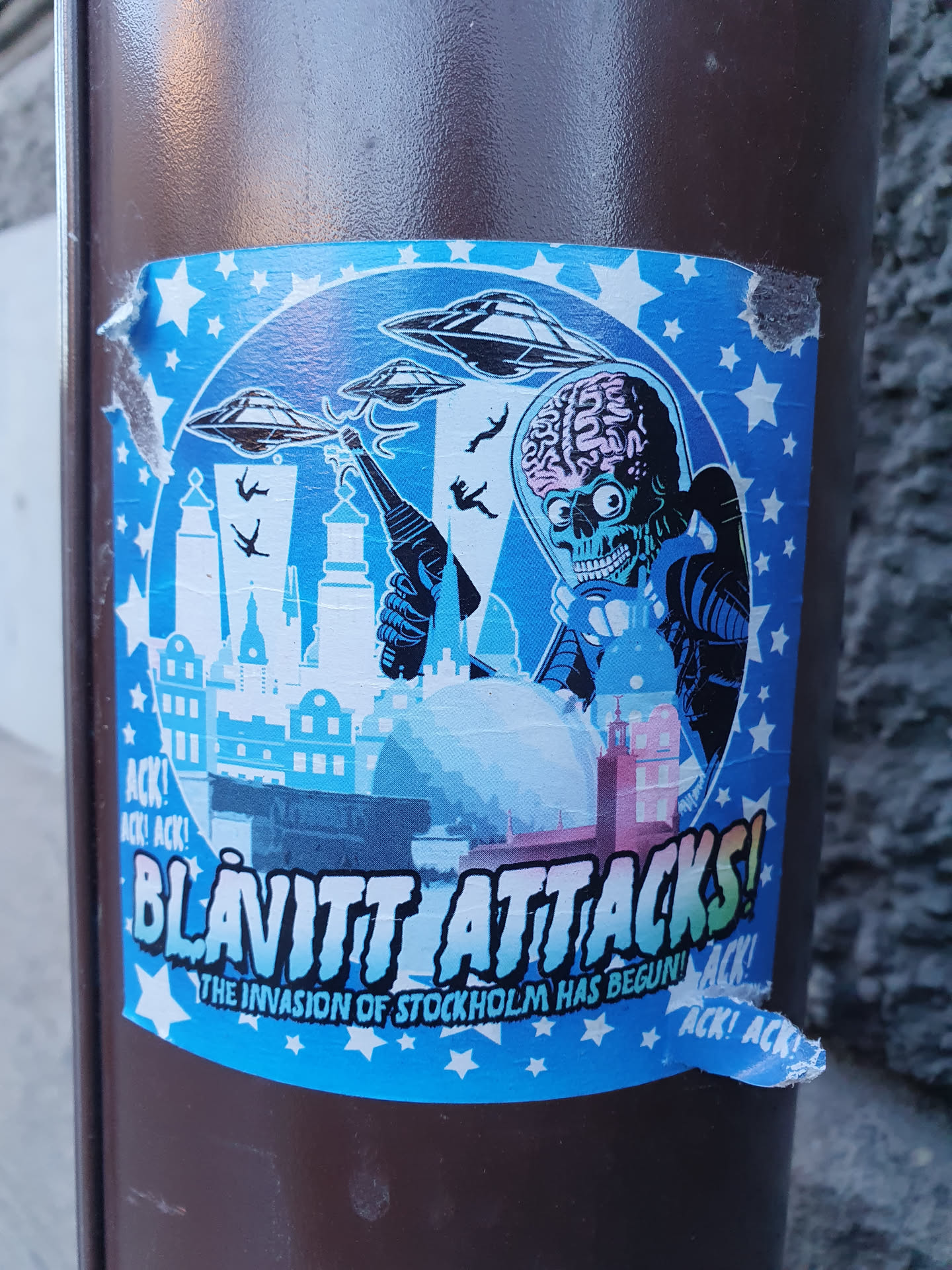 A sticker featuring a Mars Attacks illustration attacking Stockholm. The style is reminiscent of the 1960s Mars Attacks trading cards.