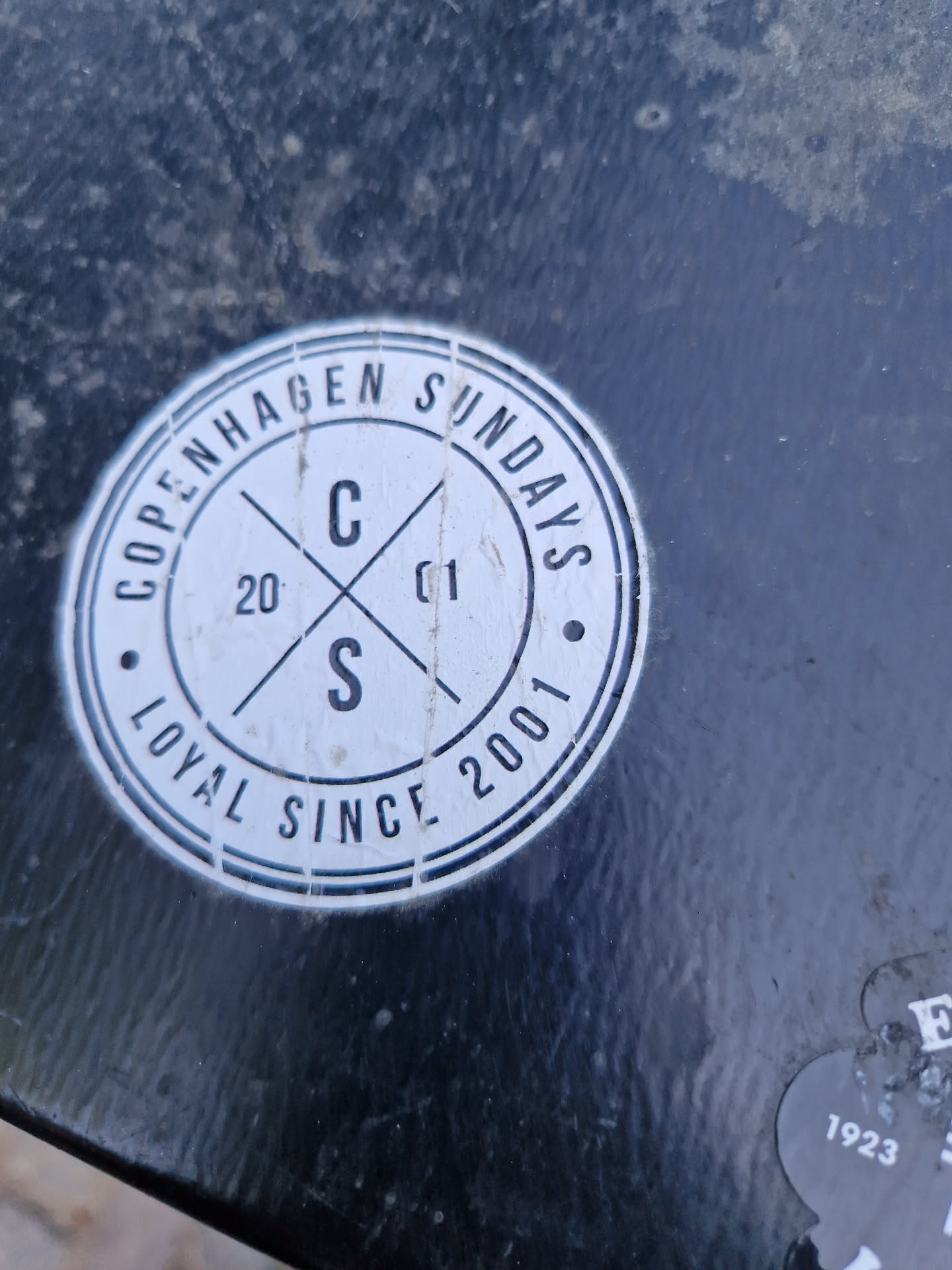 A round sticker with the text "Copenhagen Sundays" in a circular design. In the center, there is a logo with a "C" and an "S" crossed, and the numbers "20" and "01" on either side.  The text "Loyal Since 2001" is also visible at the bottom.