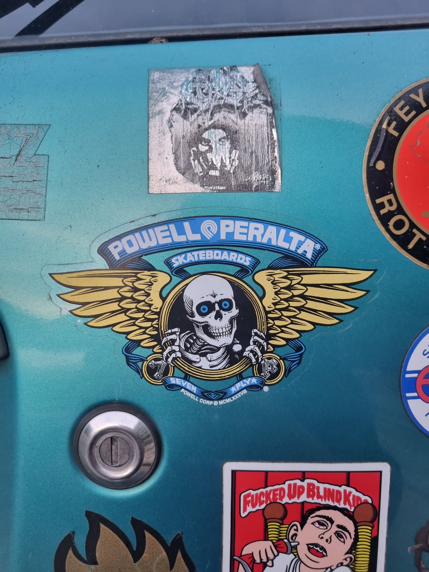 A sticker featuring the iconic Powell Peralta skull and wings logo. The skull is depicted with glowing blue eyes and is set within a circular frame. The wings are large and outstretched, giving a sense of movement and freedom. The words "Powell Peralta Skateboards" are written at the top of the sticker, and the words "Seven" and "Riply" are written under the skull.