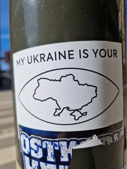 A sticker featuring a simplified outline of Ukraine within an eye shape. The text 'MY UKRAINE IS YOUR' is printed at the top. 