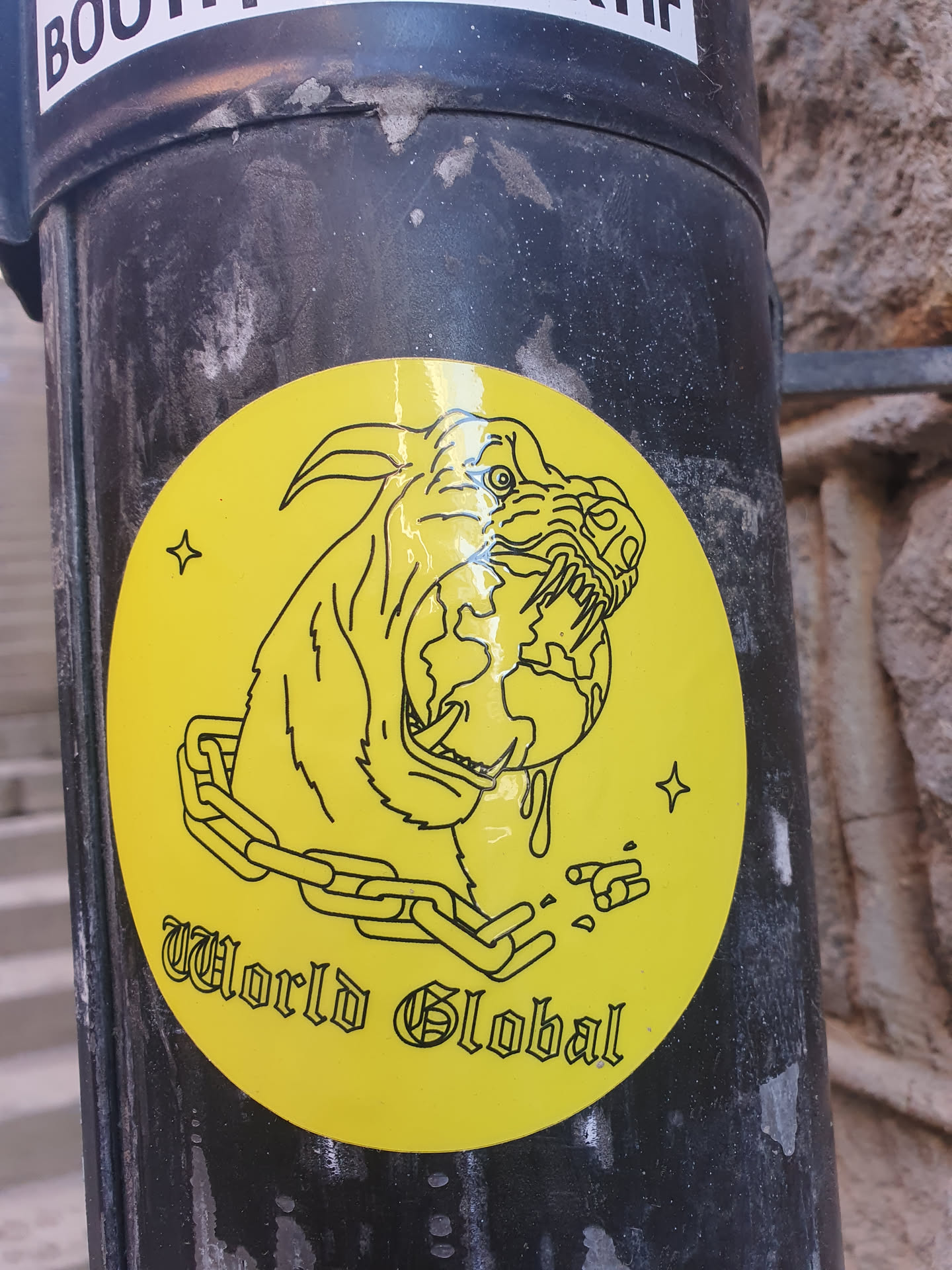 Yellow circular sticker with a line drawing of a dog's head with the Earth in its mouth, surrounded by a chain. The text "World Global" is written below the image.