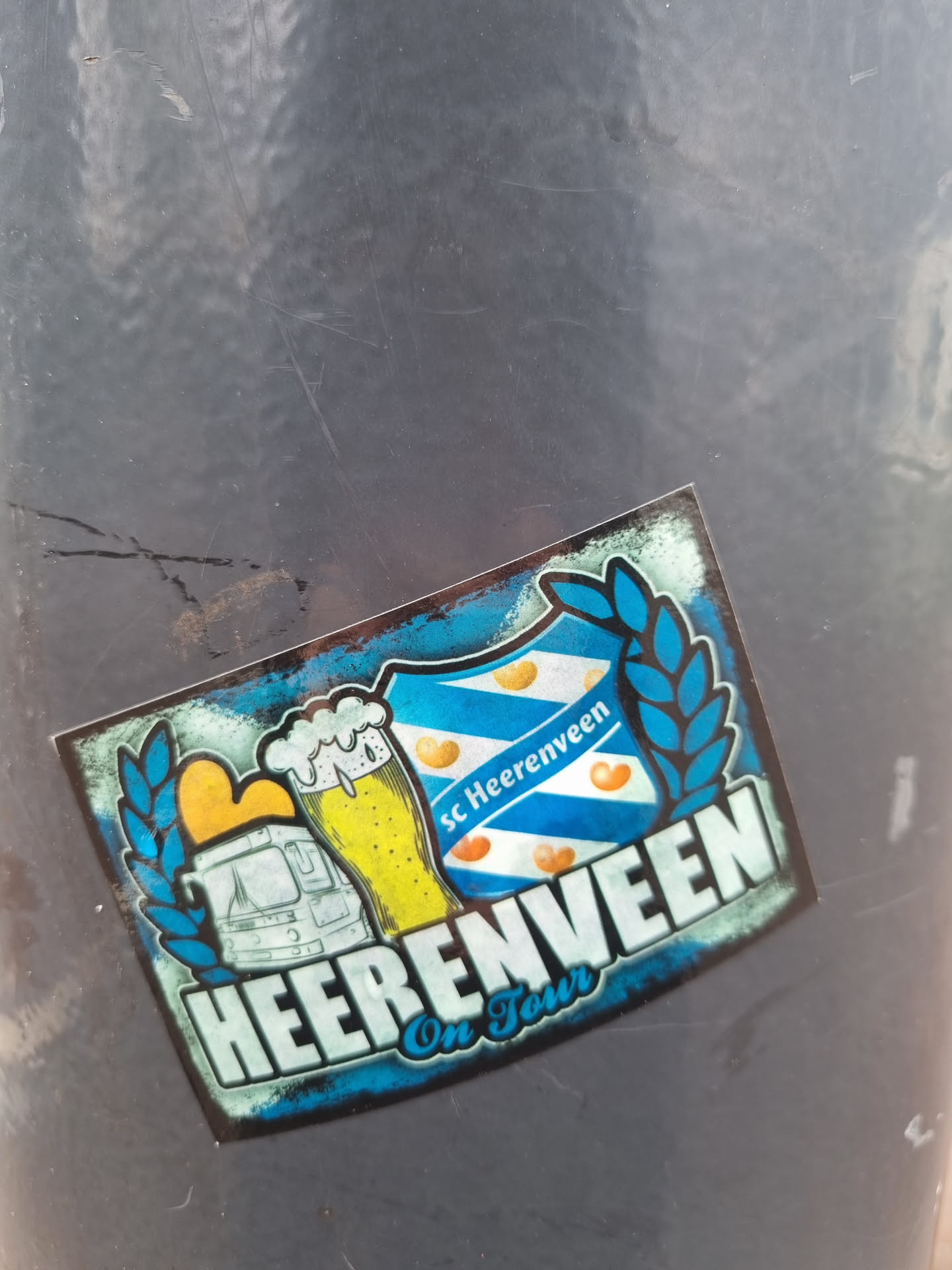 A sticker featuring the logo of SC Heerenveen, a Dutch football club, along with imagery suggesting a tour or travel theme.  It includes a beer stein, a bus, and the club's crest.