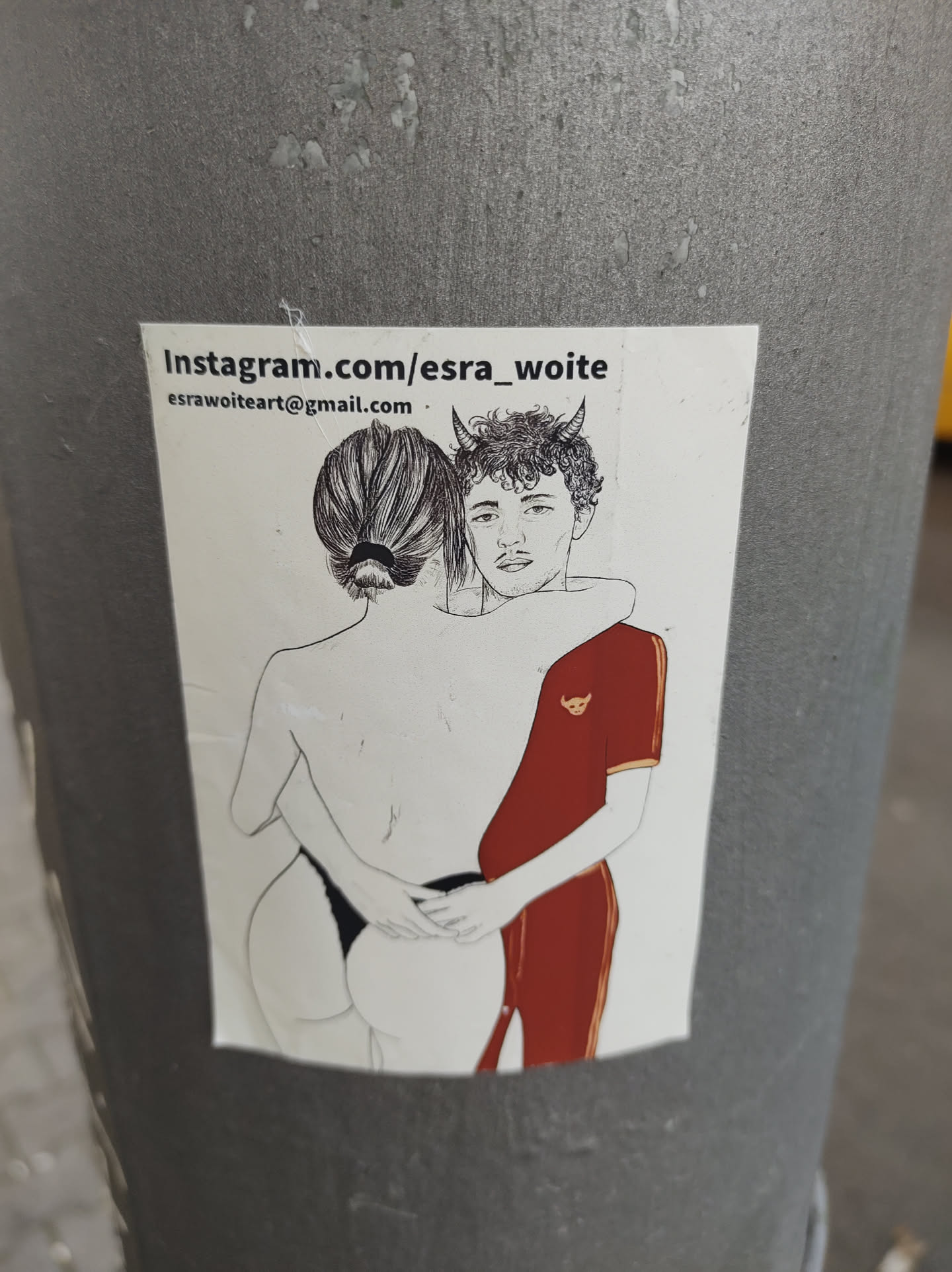 A sticker featuring a line drawing of a couple embracing. The style is minimalist and slightly suggestive. The man has small horns drawn on his head. The sticker includes the artist's Instagram and email address.