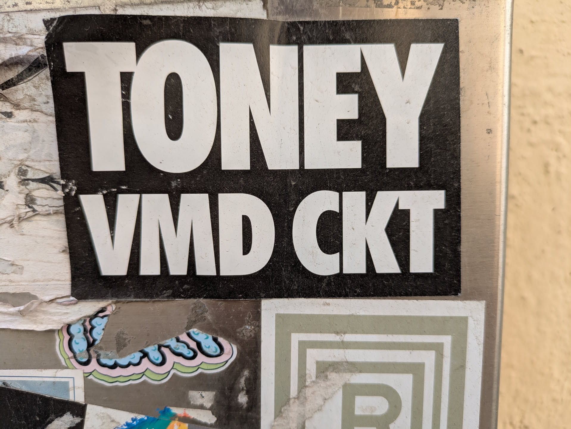 The sticker is black with white letters. The text reads "TONEY" on top and "VMD CKT" below it.