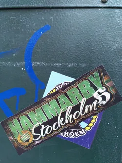 A sticker featuring the text Hammarby Stockholm's 5. The sticker has a vintage design with green and yellow colors.  There is a smaller sticker underneath it.