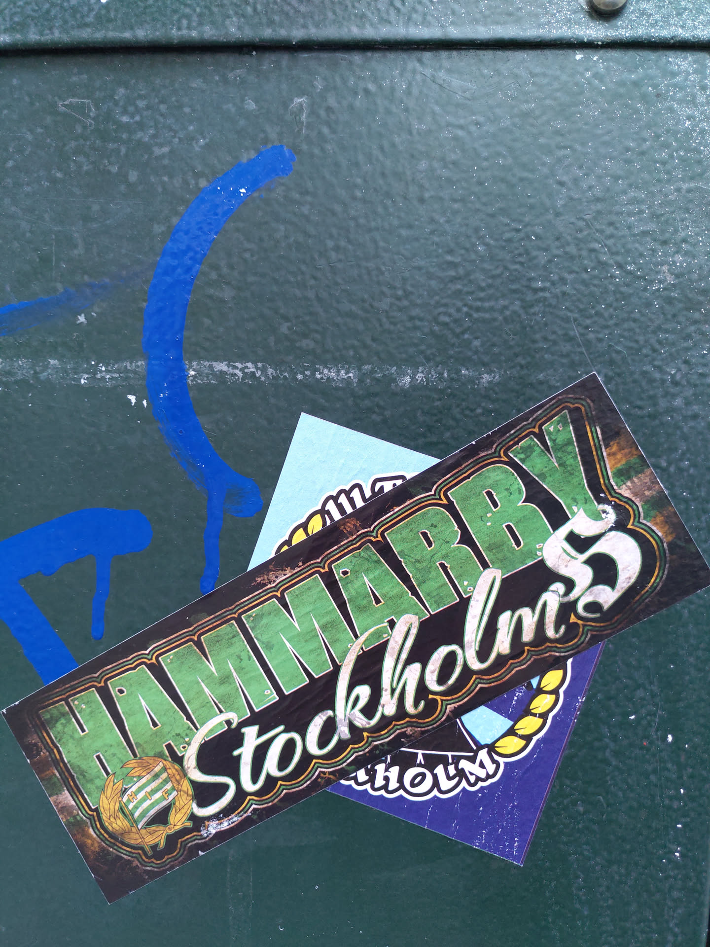 A sticker featuring the text Hammarby Stockholm's 5. The sticker has a vintage design with green and yellow colors.  There is a smaller sticker underneath it.