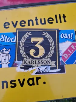 A black and gold sticker with the number 3 in the center, surrounded by a laurel wreath.  The text 'KARLSSON' is visible at the bottom. The sticker shows some signs of wear.