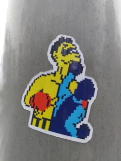 A vinyl sticker featuring pixel art of a boxer in a fighting pose. The artwork is reminiscent of classic video games. The boxer is predominantly yellow and blue, with red gloves.