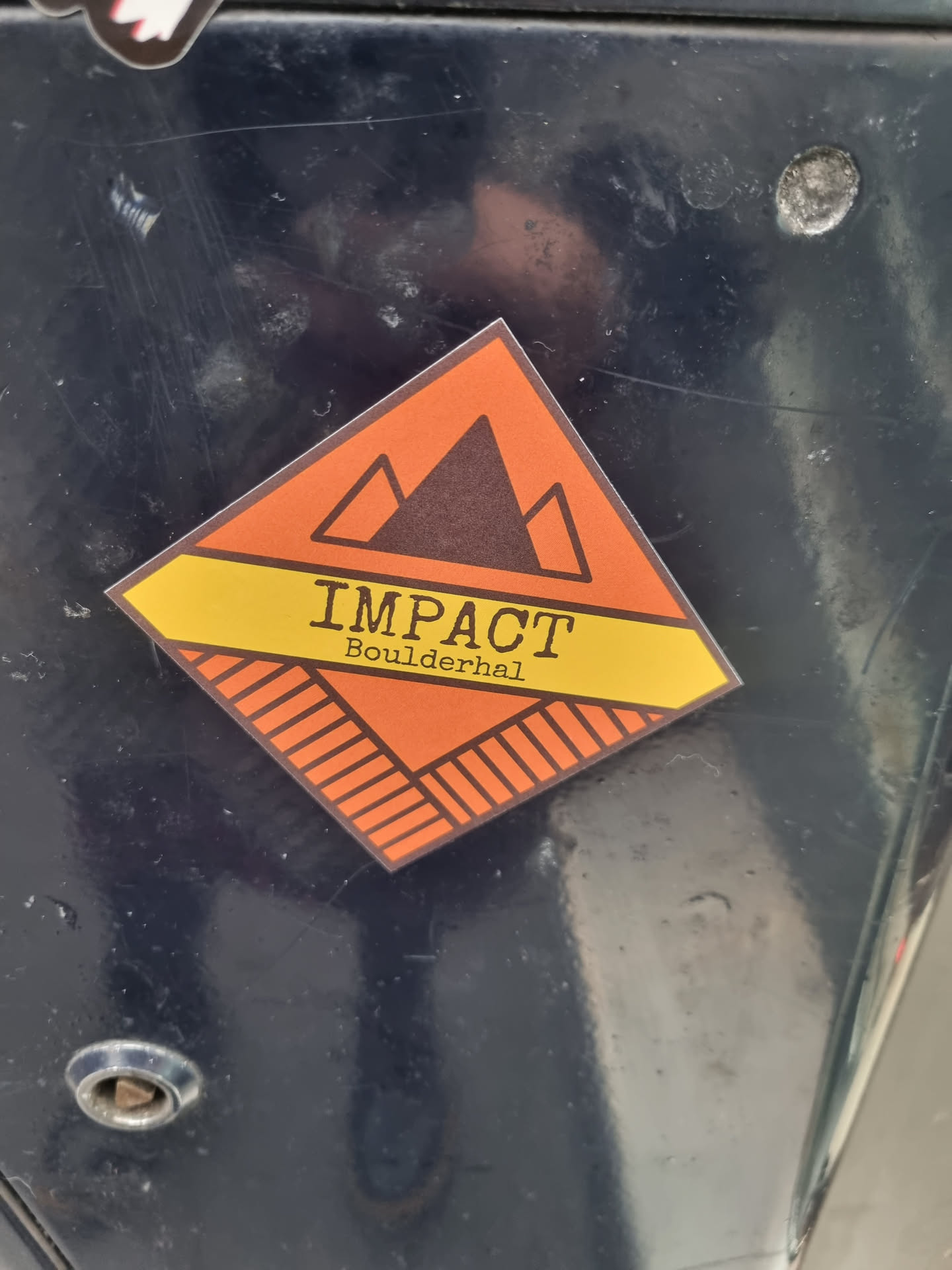 Orange and yellow diamond shaped sticker with a mountain range graphic and the text 'IMPACT' over 'Boulderhal'.