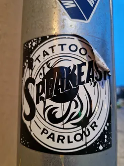 Black and white sticker with the text Speakeasy Tattoo Parlour in a circular design. The style is reminiscent of vintage tattoo flash.