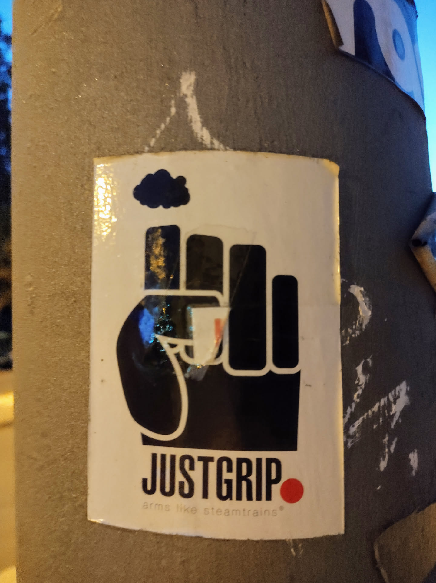 A sticker featuring a black fist with a small cloud above it. The text 'JUSTGRIP' is written below the fist, with the tagline 'arms like steamtrains' underneath.