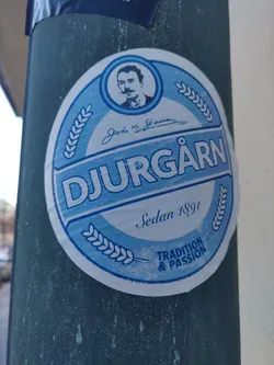 A round sticker featuring the Djurgården brewery logo. It includes a portrait of John Z. Gransson, the brewery's founder, along with the text "Djurgården", "Sedan 1891", and "Tradition & Passion". The design is simple and elegant.