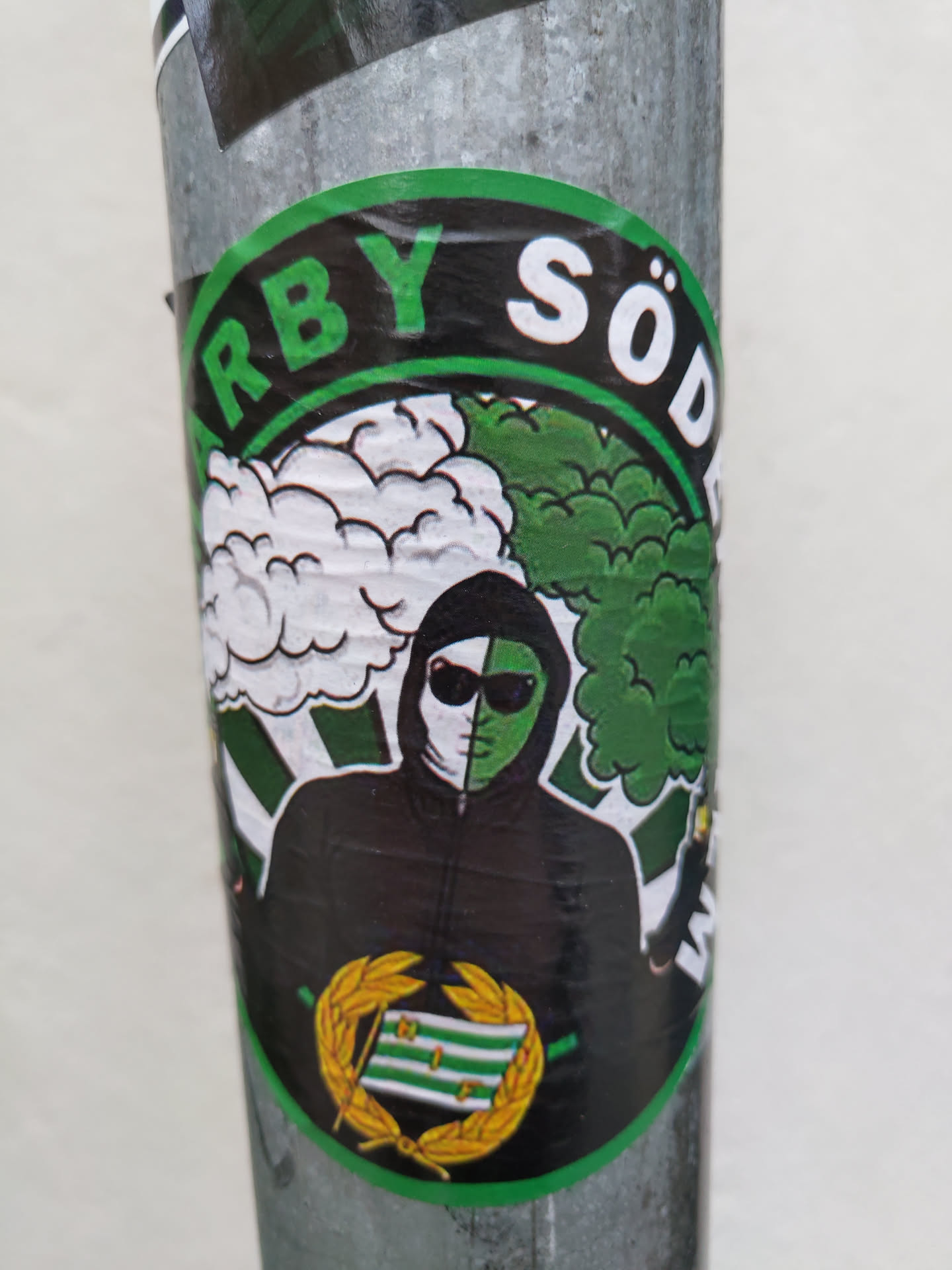 A round sticker with a green and white color scheme. It depicts a stylized figure wearing a hooded jacket and sunglasses, partially obscured by white and green clouds. The text "ARBY SÖD" is prominently displayed in a circular banner at the top. The sticker also features a laurel wreath emblem at the bottom. The style is reminiscent of street art.
